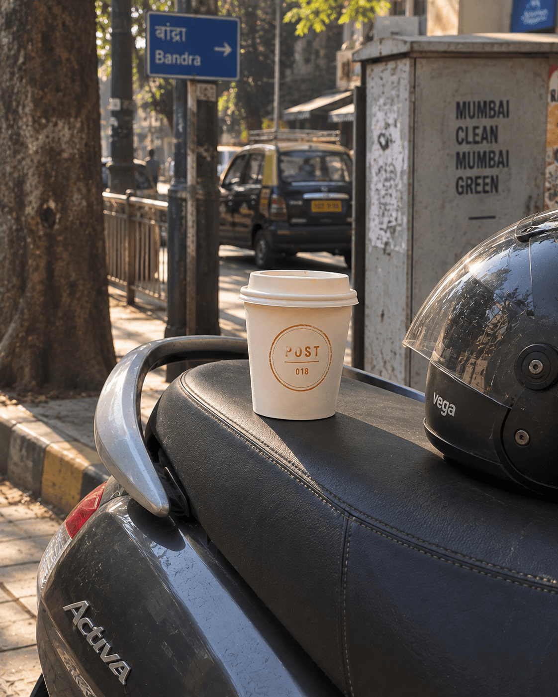 A Post coffee cup resting on a scooter seat beside a helmet on a city street.