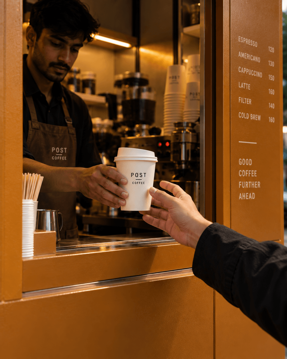 A barista passing a Post coffee cup through the kiosk window to a customer.